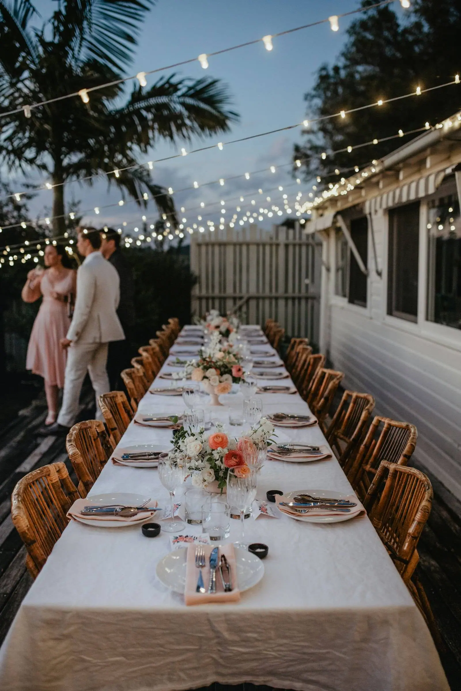 The long table under string lights at dusk